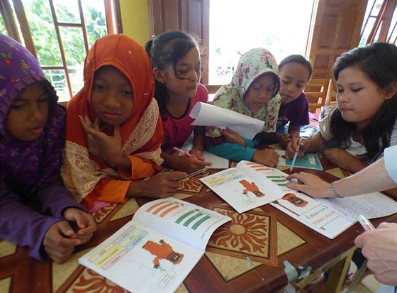 Indonéské děti se učí o ochraně deštných pralesů z materiálů, které tvoří dvě...