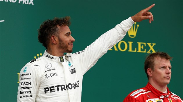 SPOKOJEN VTZ. Lewis Hamilton slav triumf ve Velk cen Britnie. Vpravo je zachmuen Kimi Rikknen.