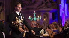 Švýcarský tenista Roger Federer s wimbledonskou trofejí kráčí na tradičním bále...