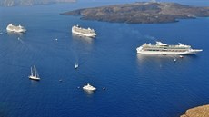 U Santorini kotví výletní lodě na moři a pasažéři se přepravují na ostrov...