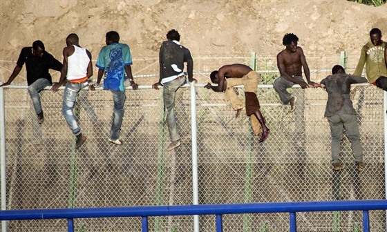 Skupina afrických uprchlík pelézá hraniní plot ve panlském pístavu...