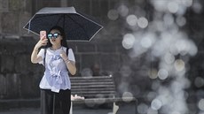 Žena si chrání hlavu před sluncem pomocí deštníku.