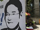 Demonstranti sedí za transparentem s podobiznou ddice konglomerátu Samsung I...