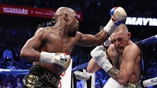 Conor McGregor (vpravo) zahnán k provazm, Floyd Mayweather diktuje tempo...