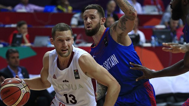 Lotyšský basketbalista Janis Strelnieks obchází Bena Mockforda z výběru Velké Británie.