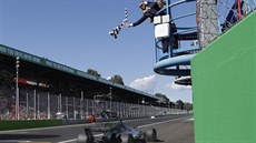 Lewis Hamilton vítzoslavn projídí cílem Velké ceny Itálie.