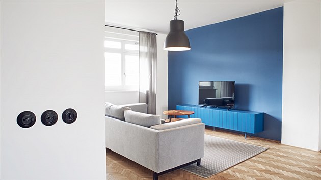 Jediný výrazný barevný prvek představuje modrá výmalba stěny a barevná skříňka pod televizor.