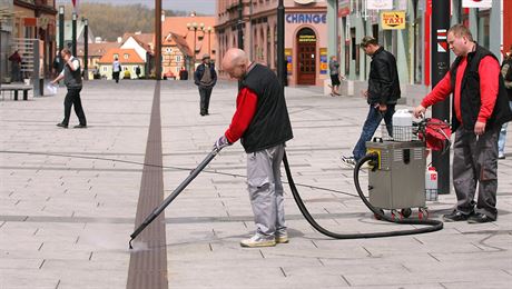 Pracovníci úklidové firmy odstraují výkaky nalepené na pí zón v Chebu.