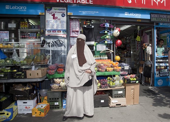 Muslimka zahalená v nikábu pózuje před pouličním krámkem v Londýně.
