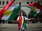 ena mává kurdskými vlajkami.