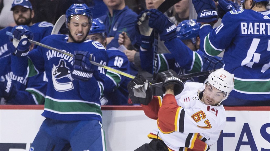 Michael Frolík z Calgary se kácí po zákroku Alexandra Burmistrova z Vancouveru.