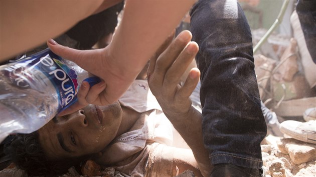 Mu� uv�zn�ný pod troskami budovy dostává napít, zatímco �eká na záchranu....