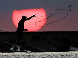 VÝCHOD SLUNCE. Rybá rozhazuje sít pi sobotním východu slunce v Port Aransas...