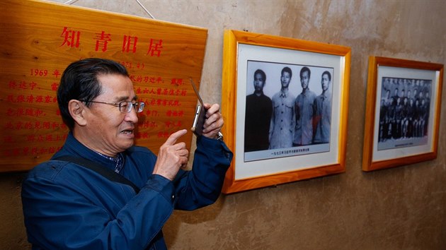 This picture taken on October 22, 2016 shows a man taking photos in a cave home where China's President Xi Jinping lived as a youth, as a photo of Xi as a youth (2nd L) hangs on the wall behind him, in Liangjiahe, in China's Shaanxi province. Three caves in a remote Chinese village where Xi Jinping was sent during the Cultural Revolution receive a constant stream of Communist pilgrims, come to pay homage four years after he came to power.