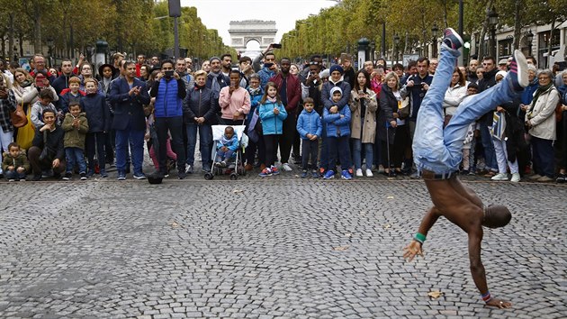 Lidé sledují vystoupení pouličního umělce na pařížské třídě Champs-Élysées.