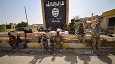 Vojáci šíitské jednotky sedí vedle vlajky Islámského státu poté, co spolu s...