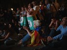 Lidé pozorují zasedání katalánského regionálního parlamentu na obrazovce na...