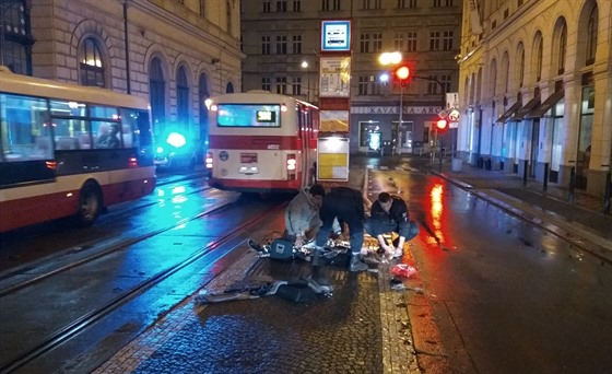 Policisté poskytují první pomoc en, kterou srazil u zastávky Masarykovo nádraí v Praze policejní vz.