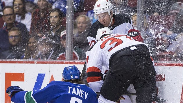 Chris Tanev z Vancouveru bojuje o puk s dvojic Jimmy Hayes , Pavel Zacha (v pedklonu) z New Jersey.