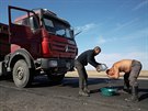 A truck driver washes himself with bottled water on the main highway for...