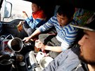 Three men eat a dinner of instant noodles and dried beef inside a truck at...