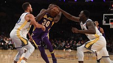 Julius Randle z LA Lakers se tlaí do zakonení pes dvojici Stephen Curry...