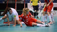 Česká florbalistka Denisa Ratajová (v červeném) se ocitla na zemi po souboji se...