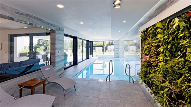 Bazén s prosklenými stěnami působí jako pokračování zahrady v interiéru. Kvetoucí zelená stěna sem přináší svěžest a živé barvy přírody.