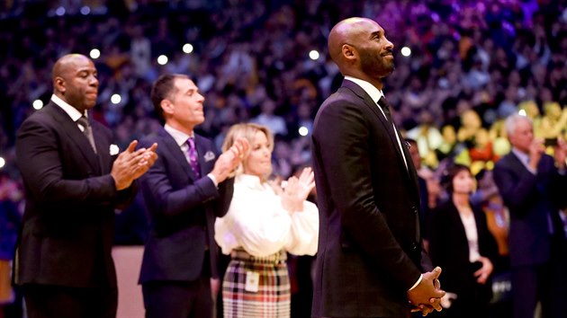 Kobe Bryant během večera, který mu LA Lakers věnovali. V pozadí klubový prezident Magic Johnson, generální manažer Rob Pelinka, který byl Bryantovým agentem, spolumajitelka klubu Jeanie Bussová.