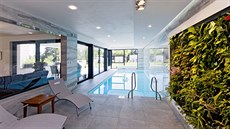 Bazén s prosklenými stěnami působí jako pokračování zahrady v interiéru....