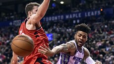 Frank Mason III. (vpravo) ze Sacramenta pihrává kolem Jakoba Pöltla z Toronta.