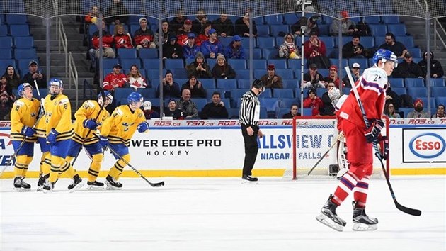 Švédští hokejisté slaví gól v utkání mistrovství světa juniorů, český reprezentant Ostap Safin zklamaně odjíždí na střídačku.
