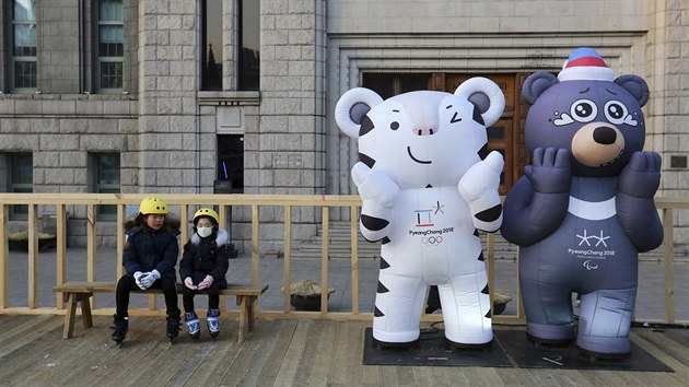 Dti sed na lavice v Soulu vedle maskot zimnch olympijskch her v Pchjongchangu  blho tygra pro olympidu a ernho medvda pro paralympidu (2. ledna 2018)