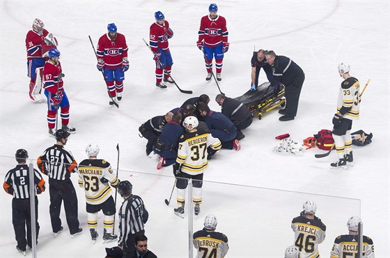 Hráči Montrealu a Bostonu sledují Philla Danaulta, jak jej lékaři ošetřují.