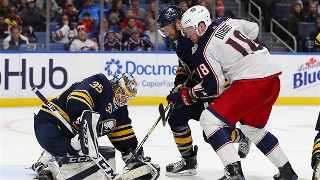 Linus Ullmark zasahuje ped Pierrem-Lucem Duboisem z Columbusu, kterho brn Marco Scandella.