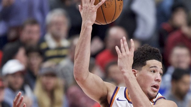 Devin Booker z Phoenixu pihrv v zpase s Portlandem, brn ho Damian Lillard.