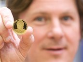 Martin Procházka drží minci, na níž je zobrazen Ivan Hlinka.