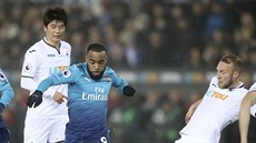 Alexandre Lacazette (v modrém) z Arsenalu se snaí uniknout Miku van der...