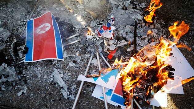 Na protest proti příjezdu severokorejského trajektu s výpravou umělců pro ZOH někteří lidé pálili vlajky.