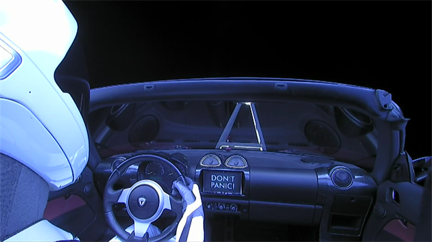Tesla Rodadster Elona Muska ve vesmru. Ped elnm sklem mete vidt drk kamery, na panelu pstrojov desky pak npis Nepanikate!, tedy hlavn heslo slavn sci-fi Stopav prvodce po Galaxii.