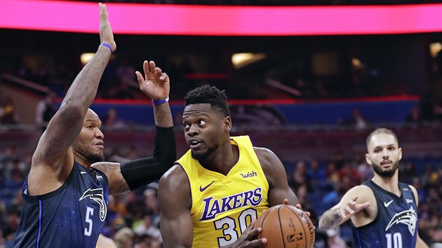 Julius Randle (ve zlatm) z LA Lakers se tla kolem Marreeseho Speightse (vlevo) ze koi Orlanda, sleduje ho Evan Fournier.