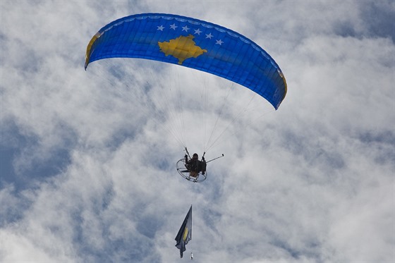Paraglidista krouží nad Prištinou s národní vlajkou před oslavami desátého...