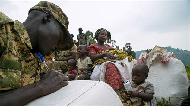 V posledních týdnech kvůli krvavým bojům mezi farmáři uprchly z Demokratické republiky Kongo desetitisíce lidí. Utíkají především do sousední Ugandy. Na snímku je právě registruje ugandský voják. (24. ledna 2018)