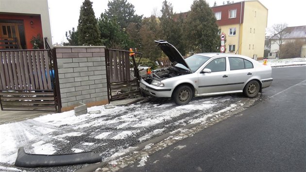 Snímek z nehody v Kostelci na Hané, kdy opilý řidič zareagoval na blikající policejní majáky stržením řízení do plotu rodinného domu. (17. 2. 2018)