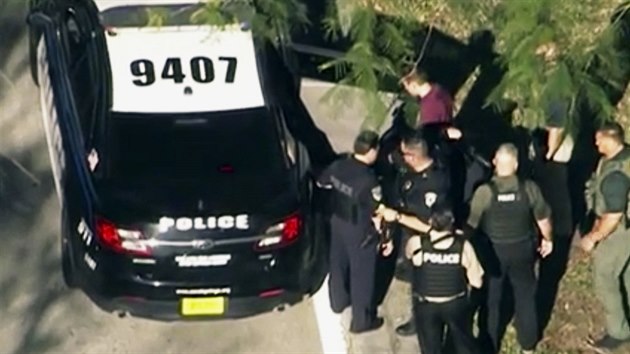 Policie po střelbě na střední škole ve floridském Parklandu zatýká muže v červeném triku. (14. února 2018)