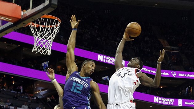 Pascal Siakam (vpravo) z Toronta jde do smee pes Dwighta Howarda z Charlotte.