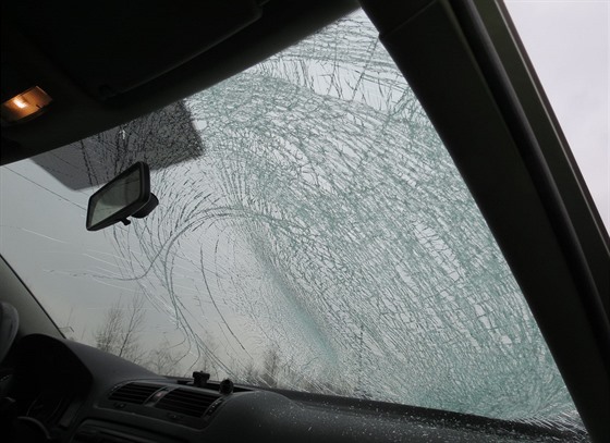 elní sklo osobního automobilu po nárazu kusu ledu z protijedoucího náklaáku.