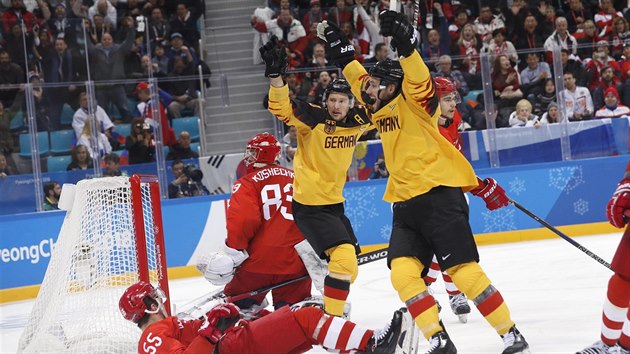 Němečtí hokejisté (v žlutočerném) se radují z branky ve finále olympijského turnaje.