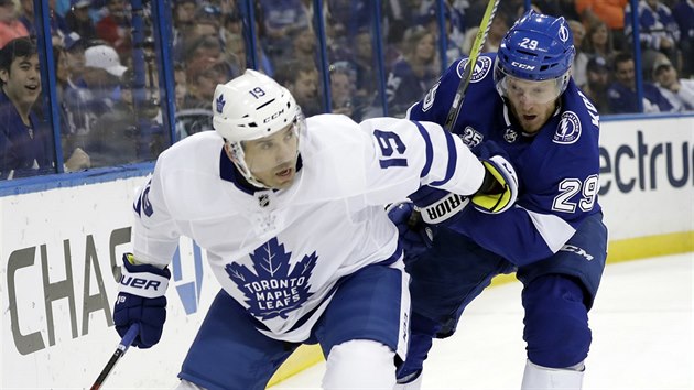 Tom Plekanec pi sv premie v dresu Toronta ujd za pukem, brzd ho  Slater Koekkoek z Tampy Bay.