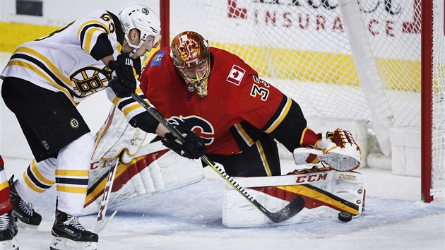 Glman Calgary David Rittich zasahuje proti stele  Brada Marchanda z Bostonu.